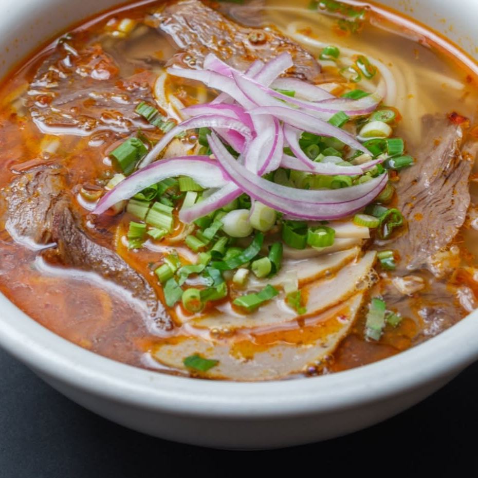 Bun bo Hue, spicy beef noodle soup topped with red onion and green onion